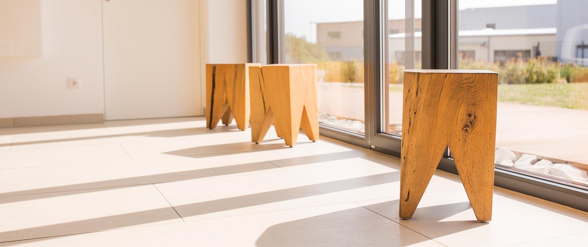Heller Wartebereich der Zahnarztpraxis mit Holzhockern.