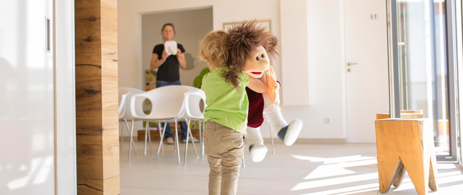 Kind spielt mit Puppe im Wartezimmer der Zahnarztpraxis.