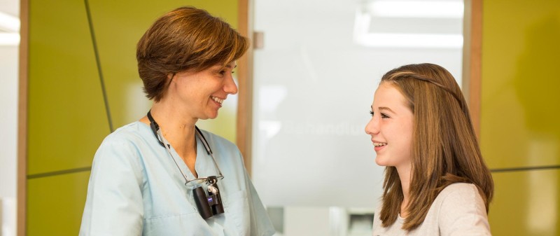 Zahnärztin im Gespräch mit junger Patientin in der Praxis.