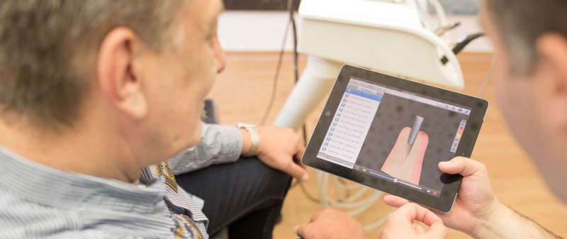 Patient erhält Beratung zur Implantologie auf Tablet in der Praxis in in Hollfeld.
