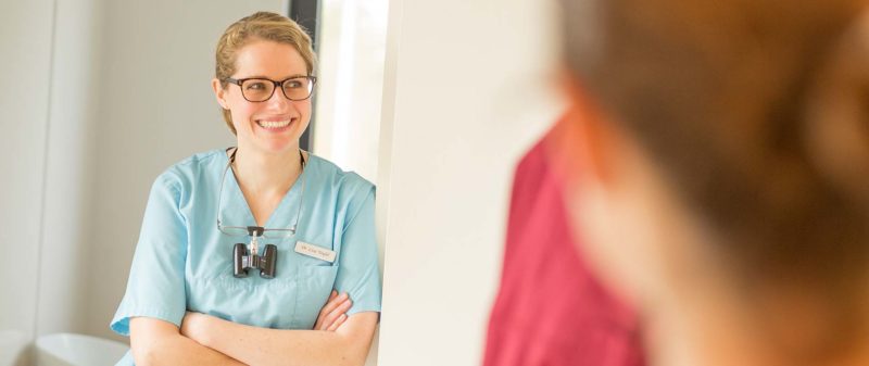 Freundliche Zahnärztin im Gespräch mit Patient in der Praxis.