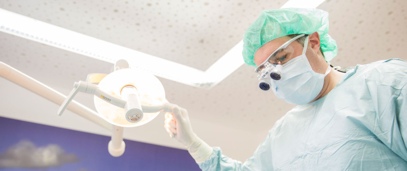 Zahnarzt Dr. Seizinger bei einer Zahnoperation unter OP-Licht.