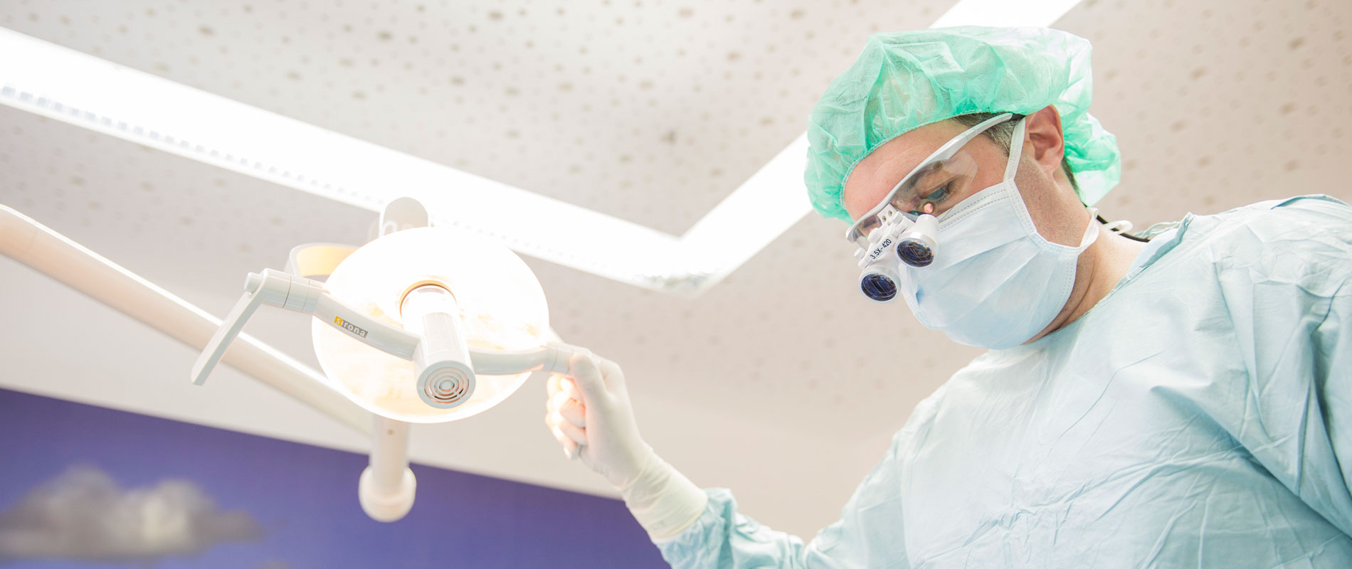 Zahnarzt Dr. Seizinger bei einer Zahnoperation unter OP-Licht.