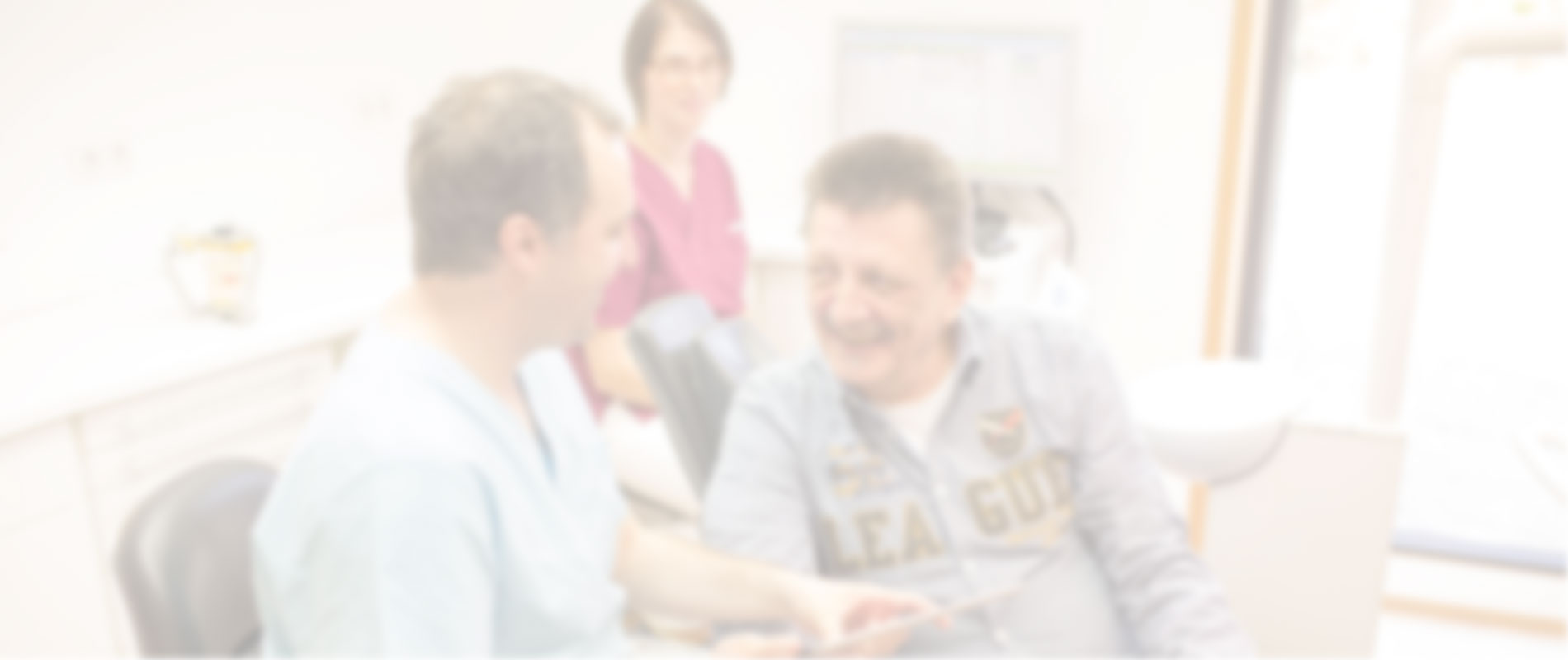 Freundliches Zahnarzt-Team berät lächelnden Patienten in der Praxis.