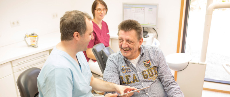 Zahnarzt berät Patienten zur Implantologie in der Praxis.