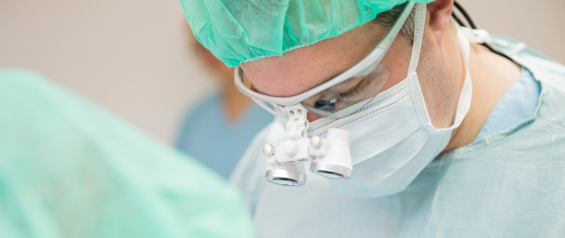 Zahnarzt bei präziser Behandlung mit Lupenbrille.