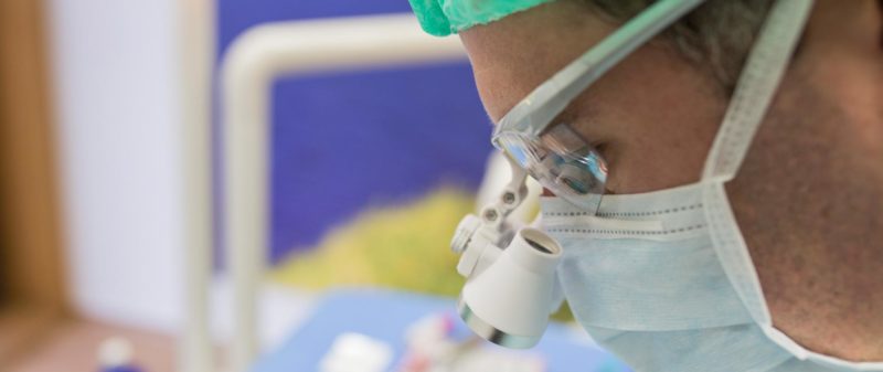 Zahnarzt bei Wurzelbehandlung mit Lupenbrille.