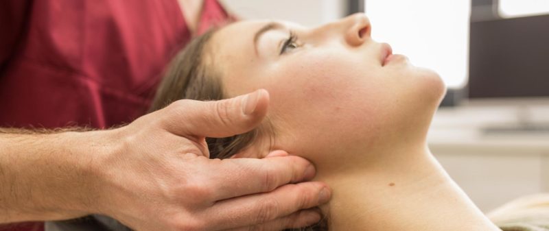 Zahnarzt untersucht Kiefergelenk einer Patientin in der Praxis.