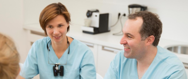 Zahnärzte im Gespräch mit Patient in der Praxis.