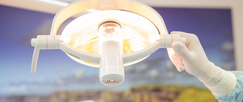 Zahnarzt justiert OP-Lampe im Behandlungsraum der Praxis.