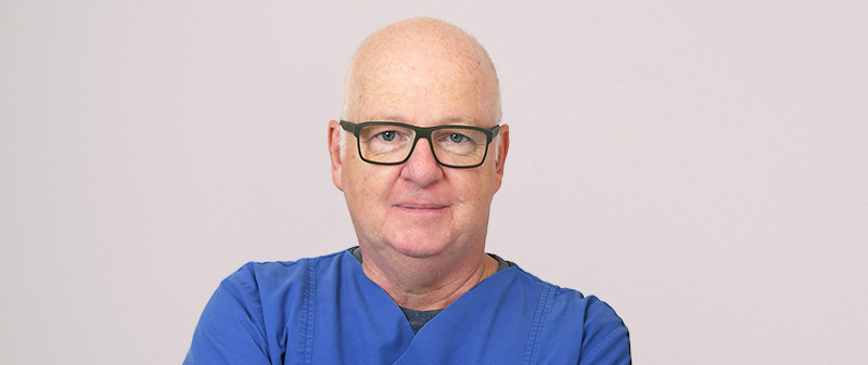 Zahnarzt in blauer Arbeitskleidung in der Praxis.