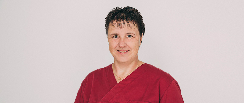 Freundliche Zahnärztin in roter Arbeitskleidung der Zahnarztpraxis in Hollfeld.