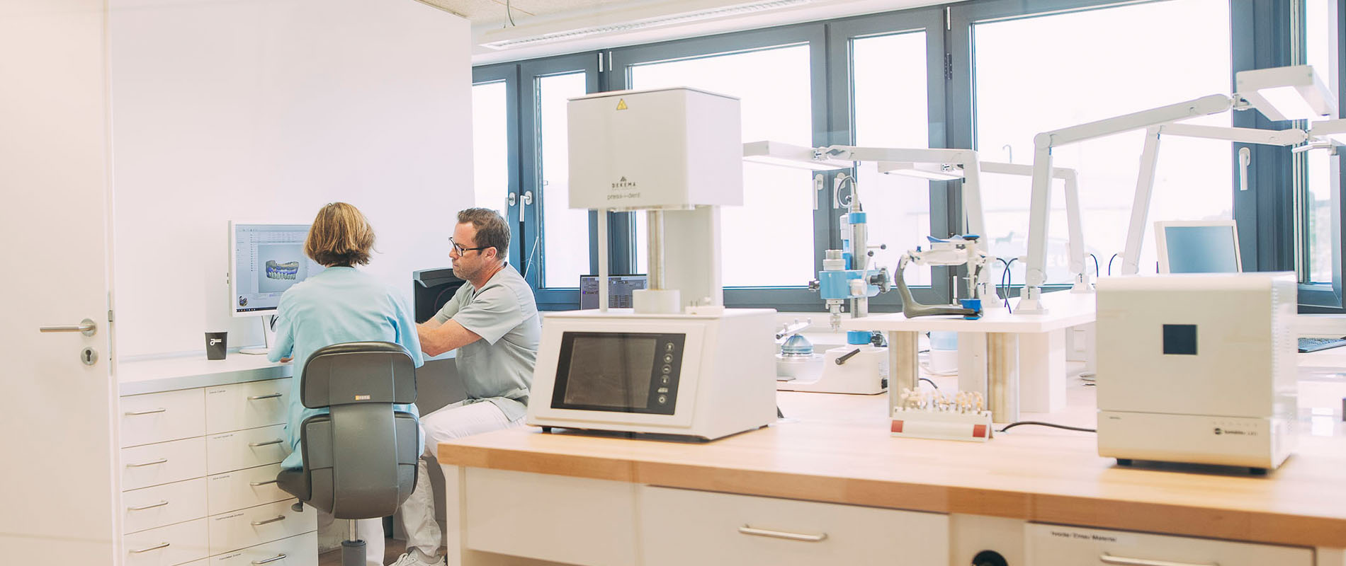 Dentallabor in Hollfeld, in dem eine Zahnärztin mit dem Zahntechnikermeister genaue Absprachen führt um ästhetisch passenden Zahnersatz zu fertigen